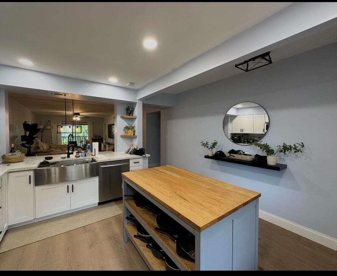 A kitchen featuring a wooden-topped island, white cabinetry, a farmhouse sink, and a round wall mirror — 701 Avenue L Apt 204a, Delray Beach FL 33483, DELRAY BEACH, FL