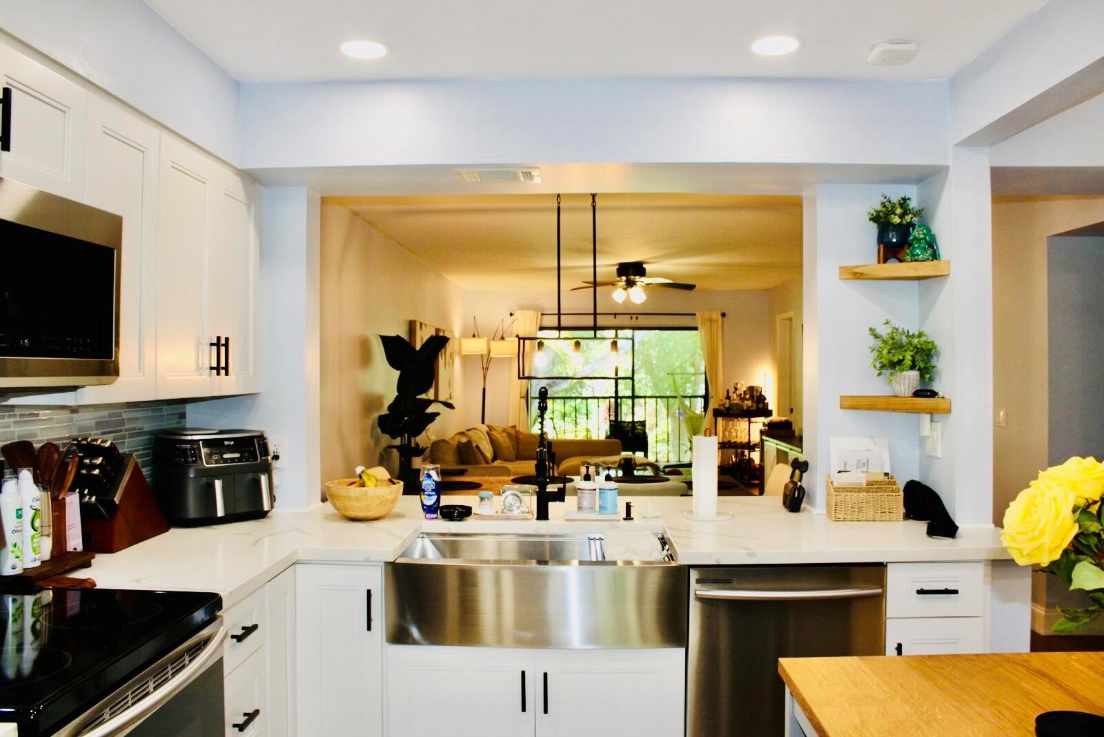 A kitchen with white cabinets, a stainless steel farmhouse sink, and an open view into the living room — 701 Avenue L Apt 204a, Delray Beach FL 33483, DELRAY BEACH, FL