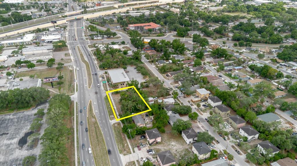 An aerial view shows a vacant, tree-covered lot outlined in yellow next to a highway — 3206 N 50TH STREET, TAMPA, FL