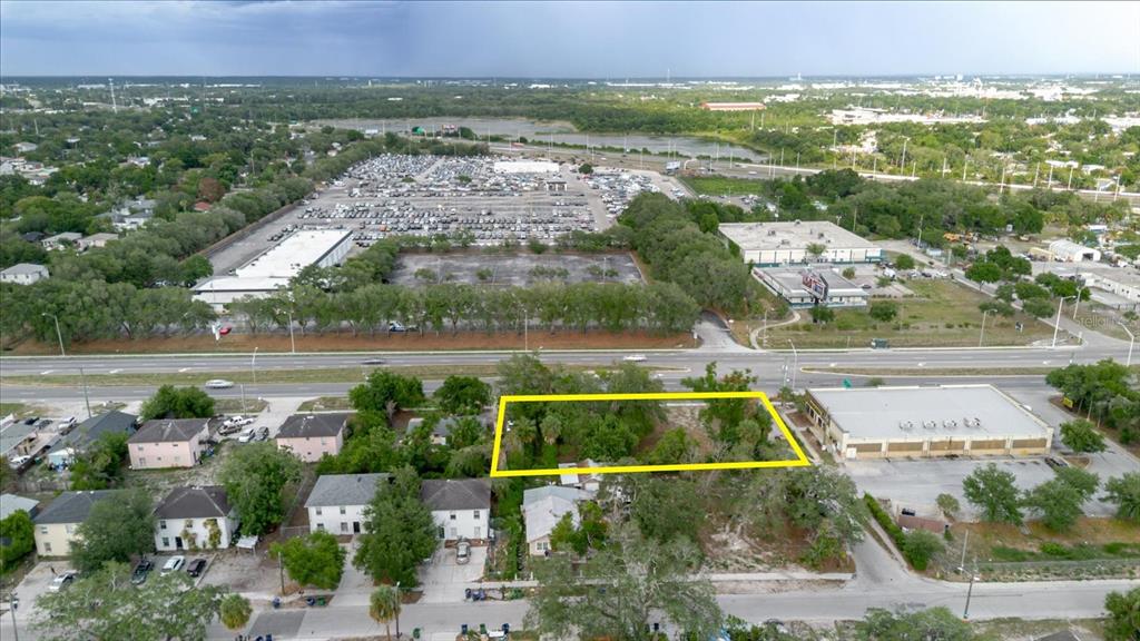 An aerial view shows a vacant, tree-covered rectangular lot outlined in yellow near a highway — 3206 N 50TH STREET, TAMPA, FL