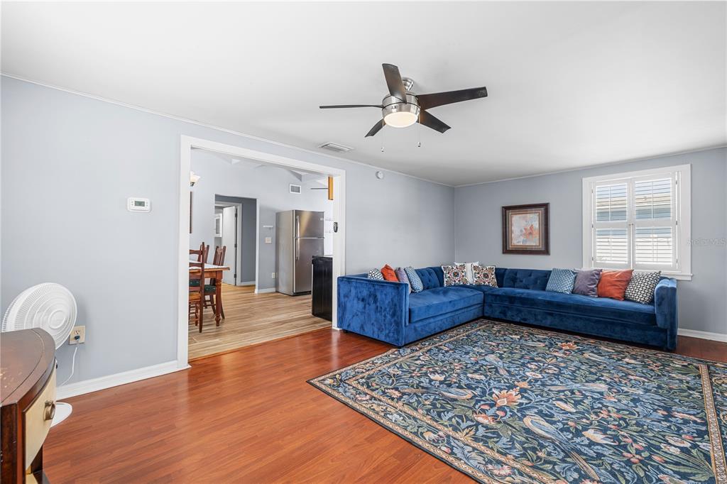 A living room features a blue sectional sofa, a patterned area rug, and hardwood floors — 6634 49TH AVENUE N, ST PETERSBURG, FL