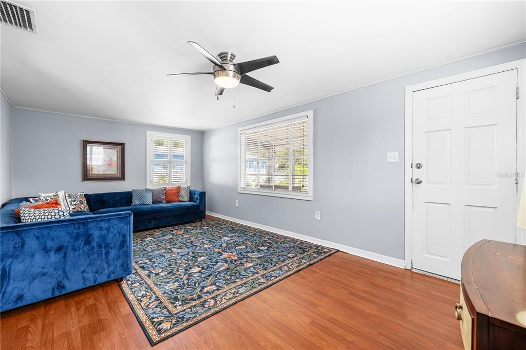 A living room features a blue sectional sofa, a patterned area rug, and wood flooring — 6634 49TH AVENUE N, ST PETERSBURG, FL