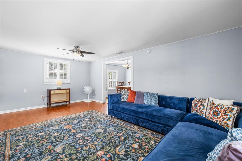 A living room features a blue sectional sofa, a patterned area rug, and hardwood floors — 6634 49TH AVENUE N, ST PETERSBURG, FL