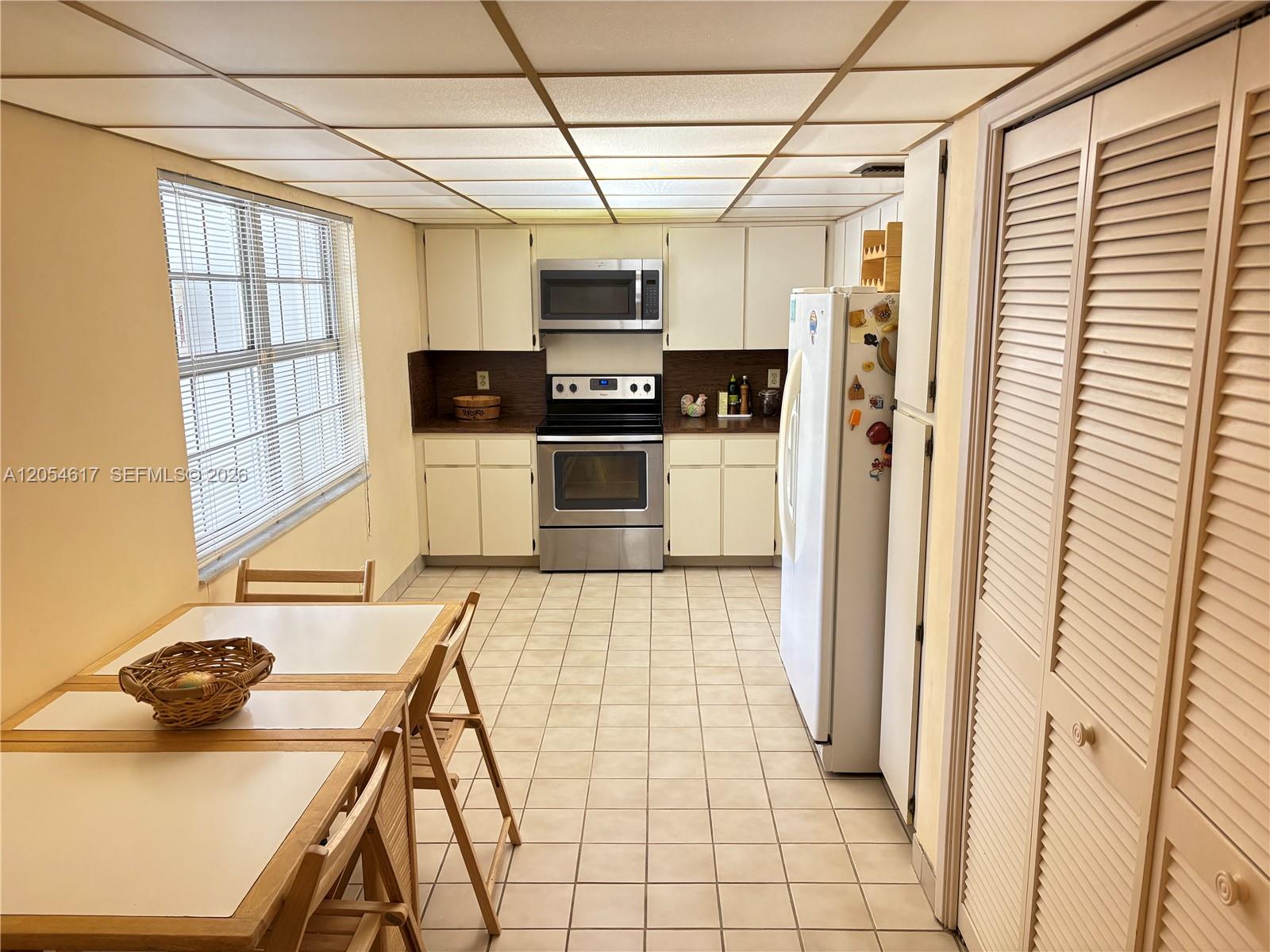 A kitchen features white cabinets, stainless steel appliances, tile flooring, and a drop ceiling — 4280 Oaks Ter # 203, Pompano Beach FL 33069, POMPANO BEACH, FL