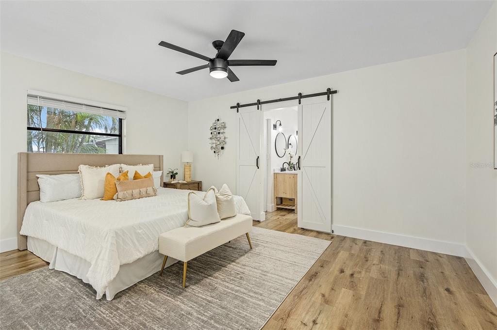 A bedroom features a king bed, a ceiling fan, and a sliding barn door entrance — 191 CASA LANE, PUNTA GORDA, FL