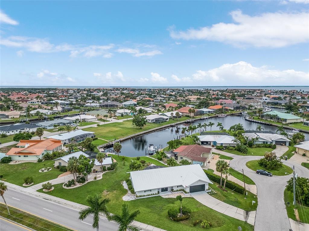 An aerial view shows a residential neighborhood with houses, a canal, and a road — 191 CASA LANE, PUNTA GORDA, FL