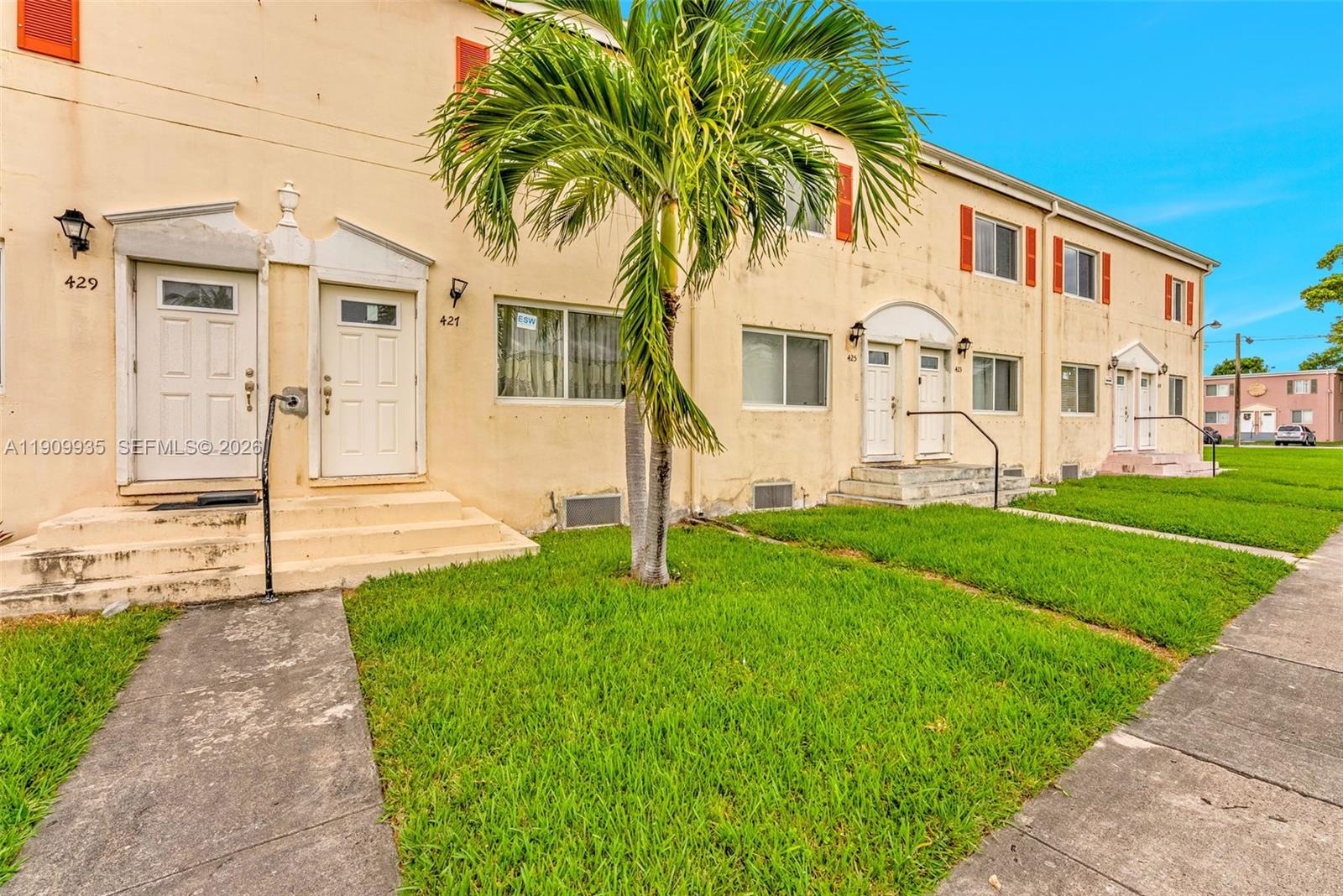 A row of two-story tan townhouses with white doors and a palm tree in front — 427 NW 84th Ter # 427, Miami FL 33150, MIAMI, FL