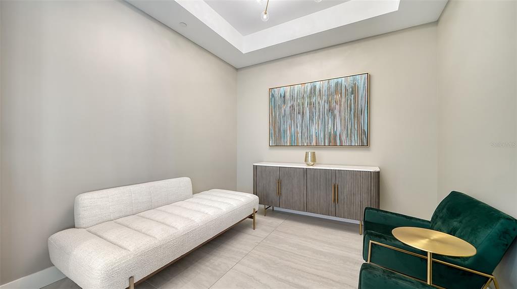 A modern room features a white daybed, a green armchair, and a wooden sideboard — 301 QUAY COMMONS DRIVE UNIT 704, SARASOTA, FL