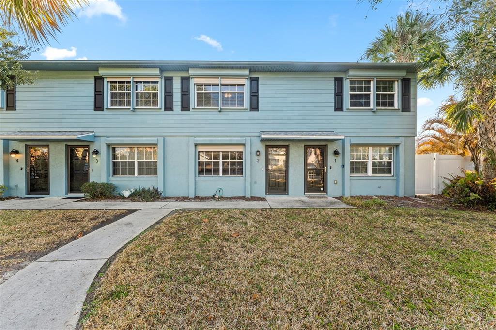 A two-story light blue townhouse exterior features multiple front doors and windows with black shutters — 101 N PINE STREET UNIT 2, NEW SMYRNA BEACH, FL