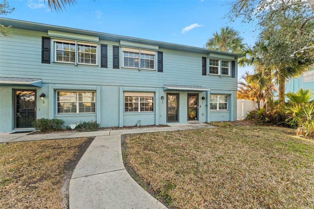 A two-story light blue townhouse exterior features a concrete walkway and a grassy front yard — 101 N PINE STREET UNIT 2, NEW SMYRNA BEACH, FL