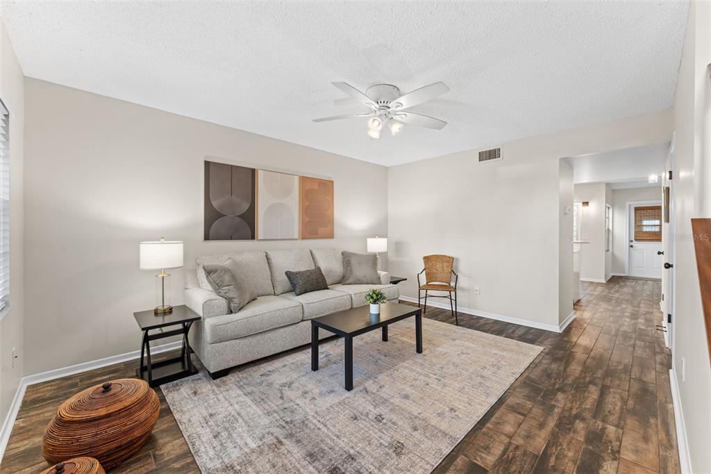A living room features a light gray sofa, a coffee table, and wood-look tile flooring — 101 N PINE STREET UNIT 2, NEW SMYRNA BEACH, FL