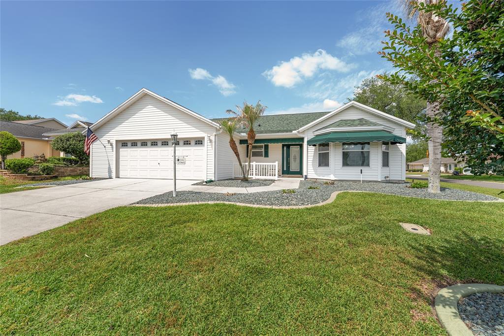 A single-story house with a white exterior, a two-car garage, and a green lawn — 17602 SE 82ND WOODLAWN AVENUE, THE VILLAGES, FL