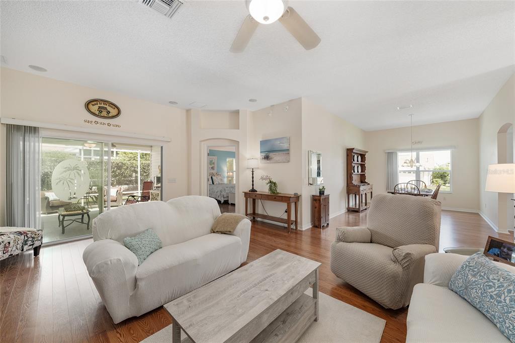 A living room features a white sofa, a beige armchair, a coffee table, and wood flooring — 17602 SE 82ND WOODLAWN AVENUE, THE VILLAGES, FL