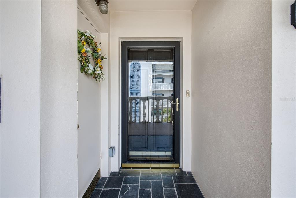 A black storm door with a decorative wreath sits at the entrance of a home — 131 BLUFF VIEW DRIVE UNIT 401, BELLEAIR BLUFFS, FL