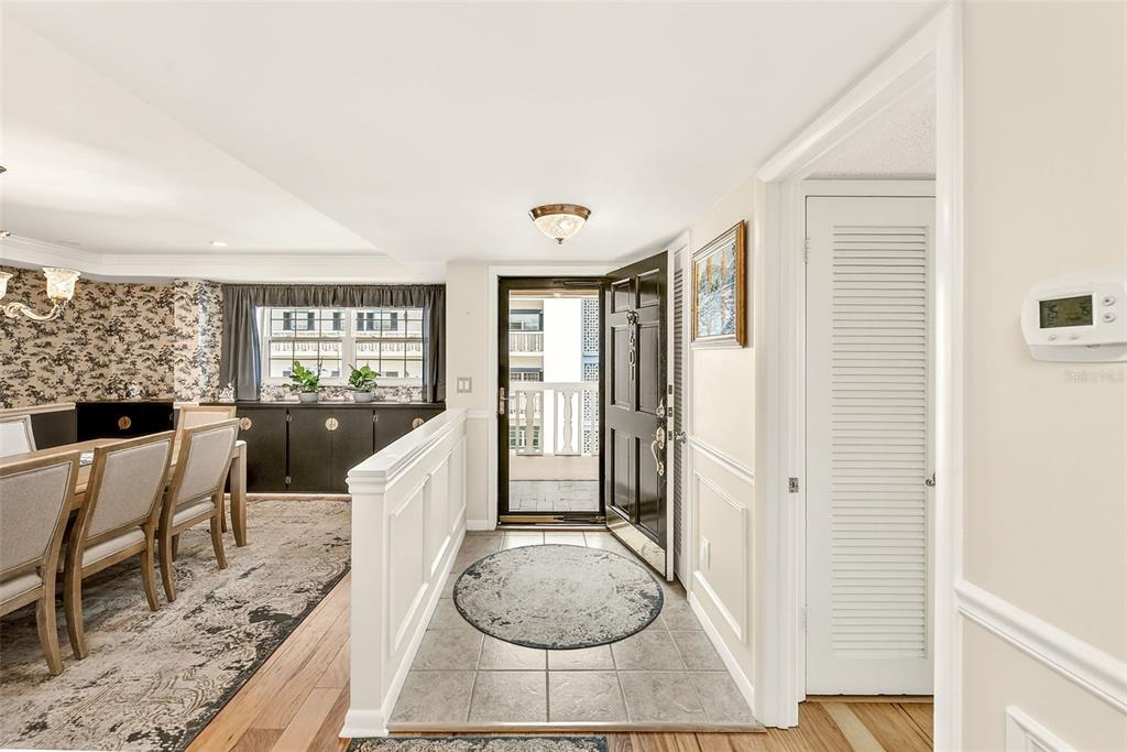 An entryway with a tiled floor leads to a front door and a dining area — 131 BLUFF VIEW DRIVE UNIT 401, BELLEAIR BLUFFS, FL