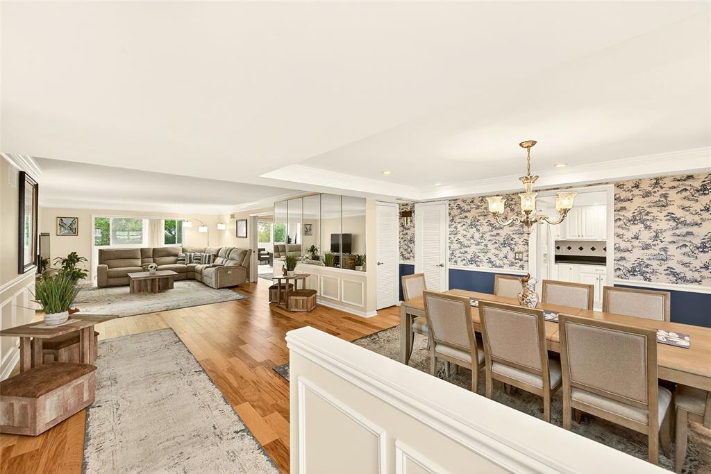 An open-concept living and dining area features hardwood floors, a mirrored wall, and wallpaper — 131 BLUFF VIEW DRIVE UNIT 401, BELLEAIR BLUFFS, FL