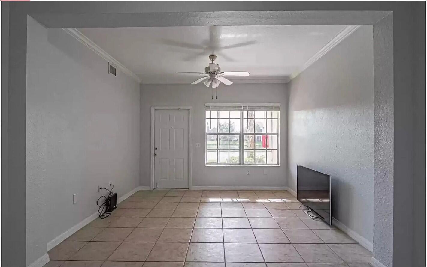 An empty living room with light gray walls, tile flooring, a ceiling fan, and window — 2308 57th Circle # 2308, Vero Beach FL 32966, VERO BEACH, FL