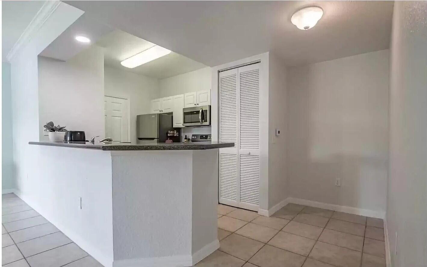 A kitchen with white cabinets, stainless steel appliances, and a breakfast bar overlooking a room — 2308 57th Circle # 2308, Vero Beach FL 32966, VERO BEACH, FL