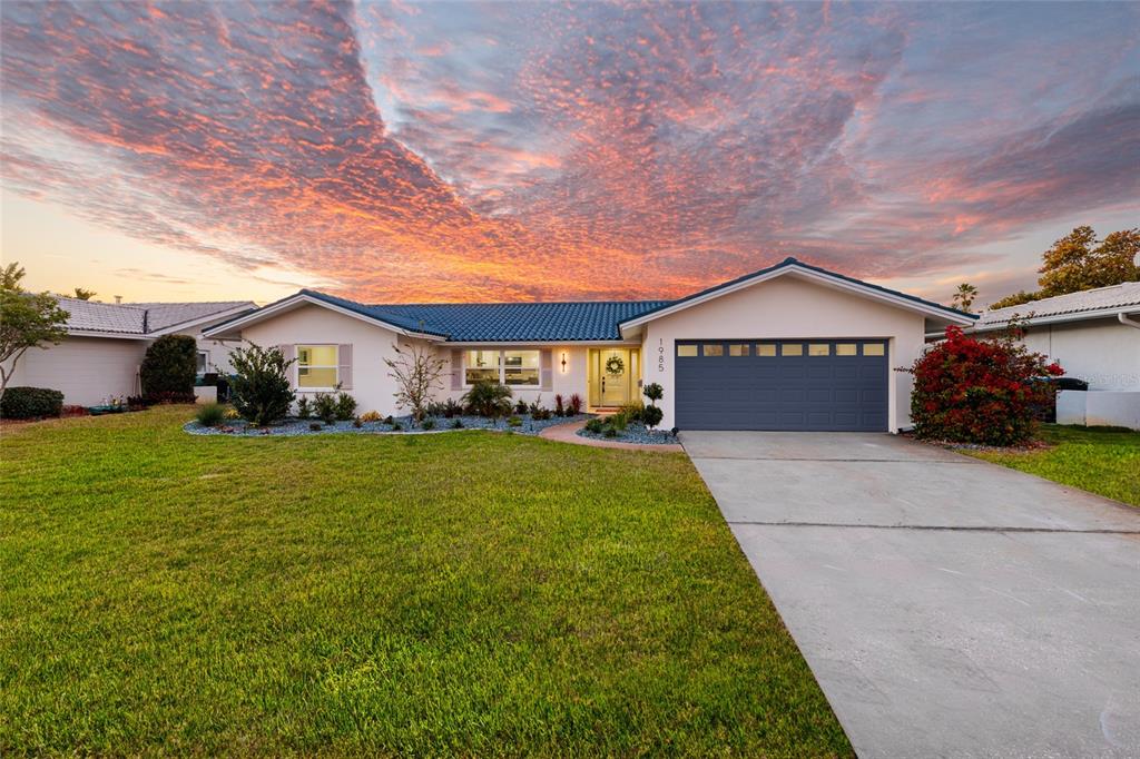 A single-story house with a blue tiled roof and a two-car garage at sunset — 1985 MICHIGAN AVENUE NE, ST PETERSBURG, FL