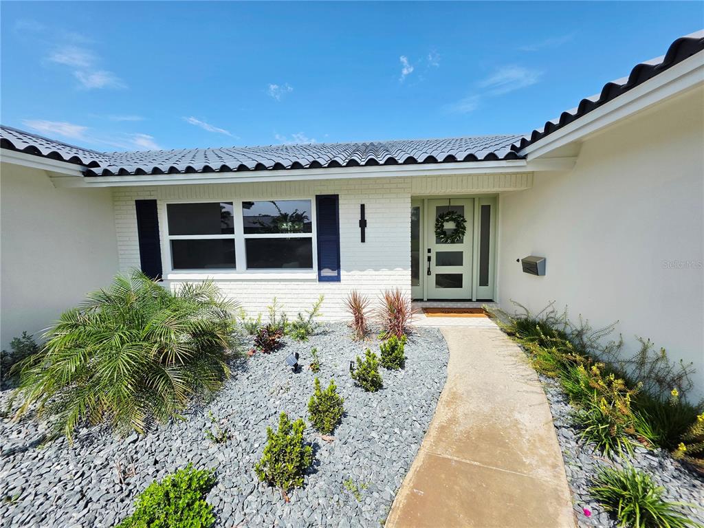 A white brick house exterior features a light green front door and a rock garden — 1985 MICHIGAN AVENUE NE, ST PETERSBURG, FL