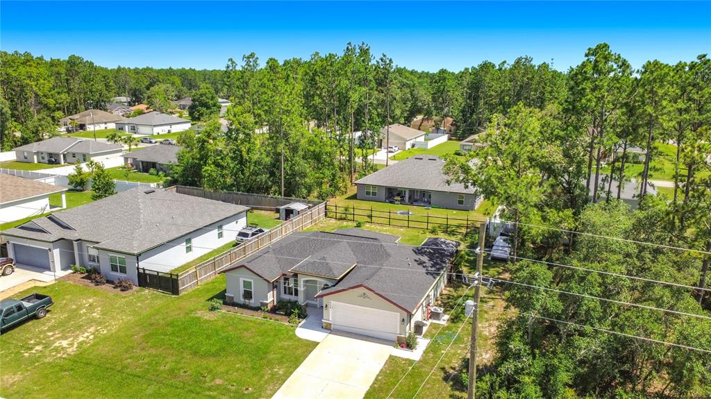 An aerial view shows a suburban neighborhood with several single-story houses and wooded areas — 628 MARION OAKS TRAIL, OCALA, FL