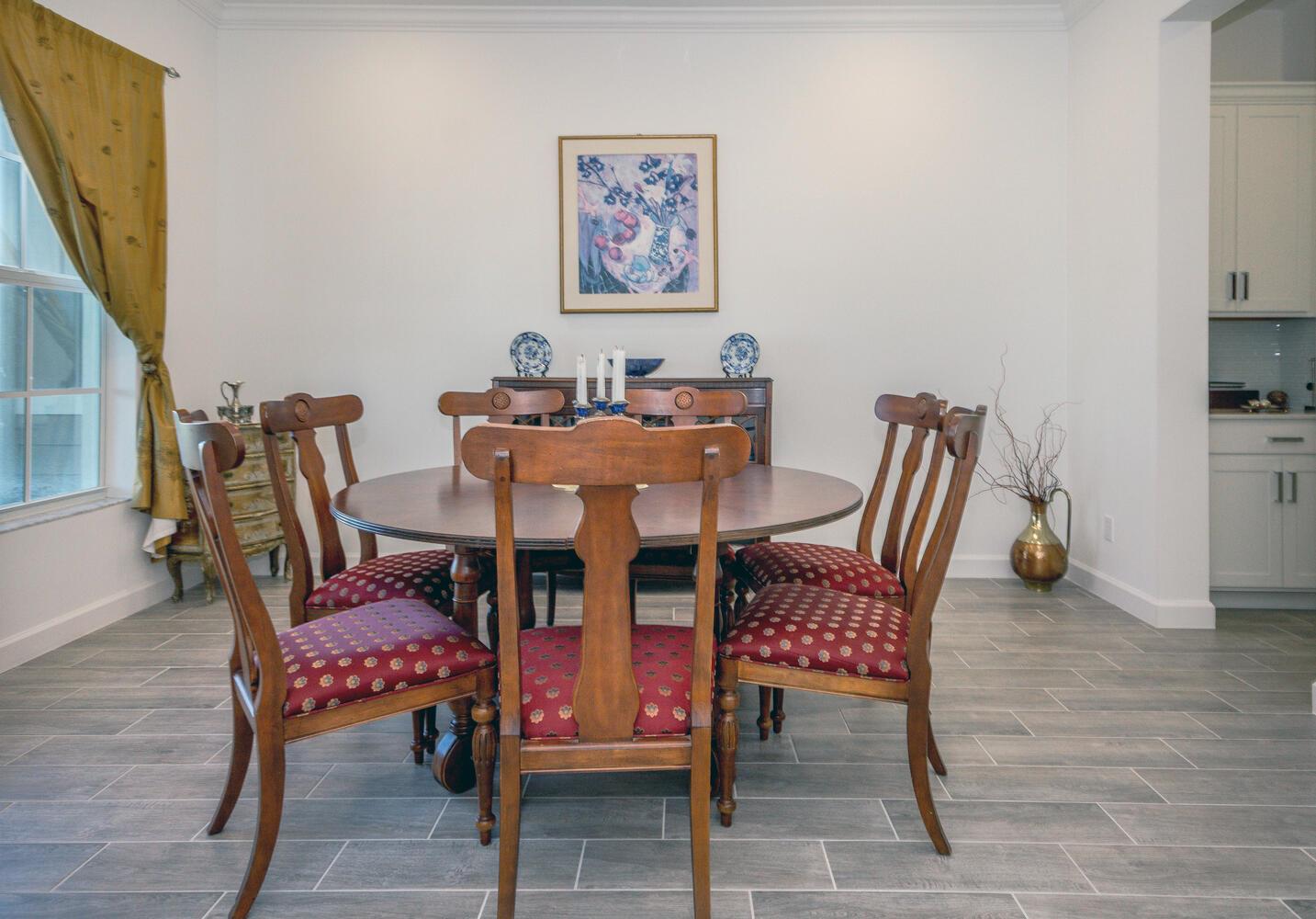 A dining room features a round wooden table, six patterned chairs, and gray tile flooring — 714 Hookline Circle, Loxahatchee FL 33470, LOXAHATCHEE, FL