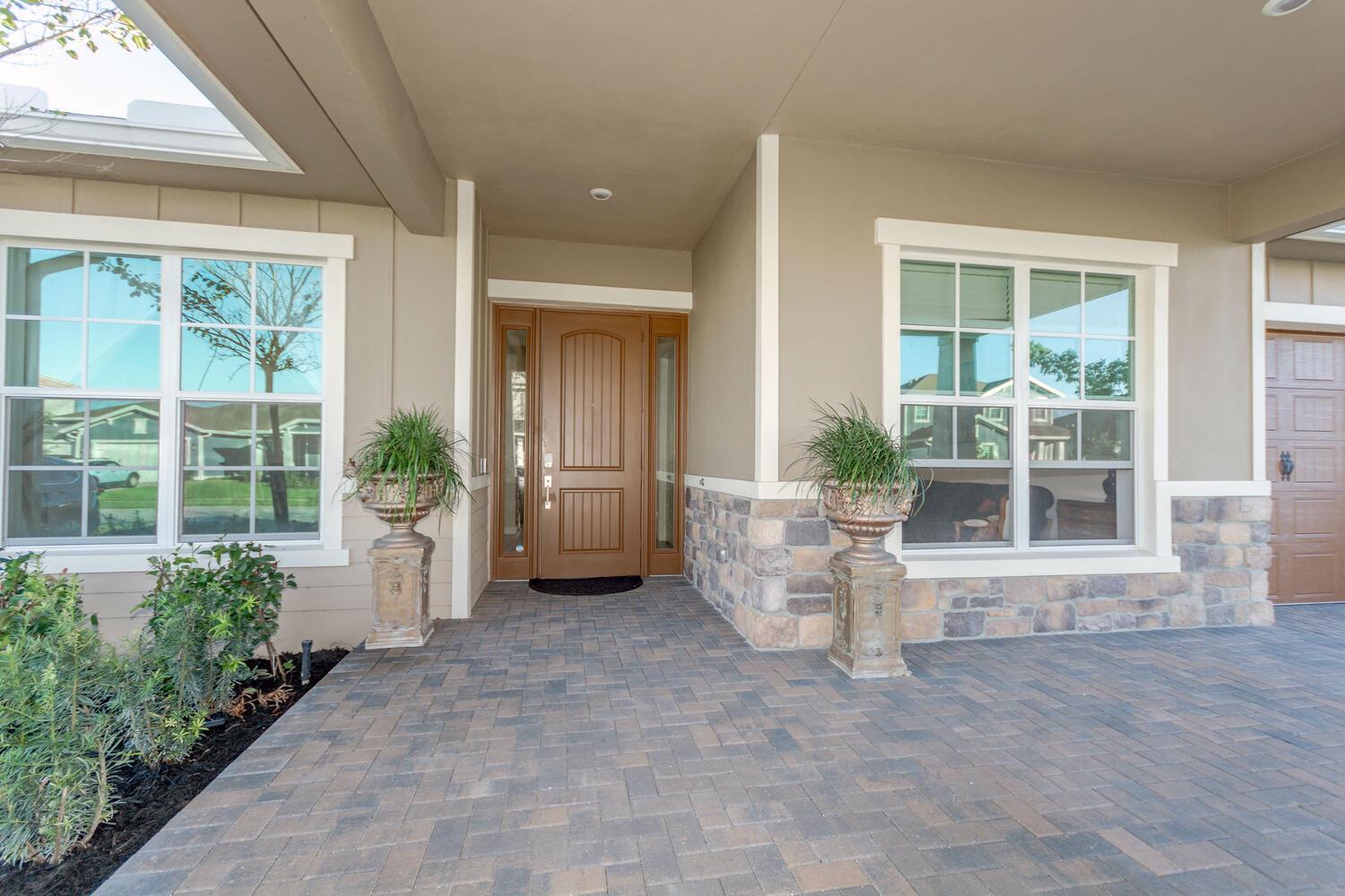 The exterior of a house features a stone-accented facade, a brown front door, and pavers — 714 Hookline Circle, Loxahatchee FL 33470, LOXAHATCHEE, FL