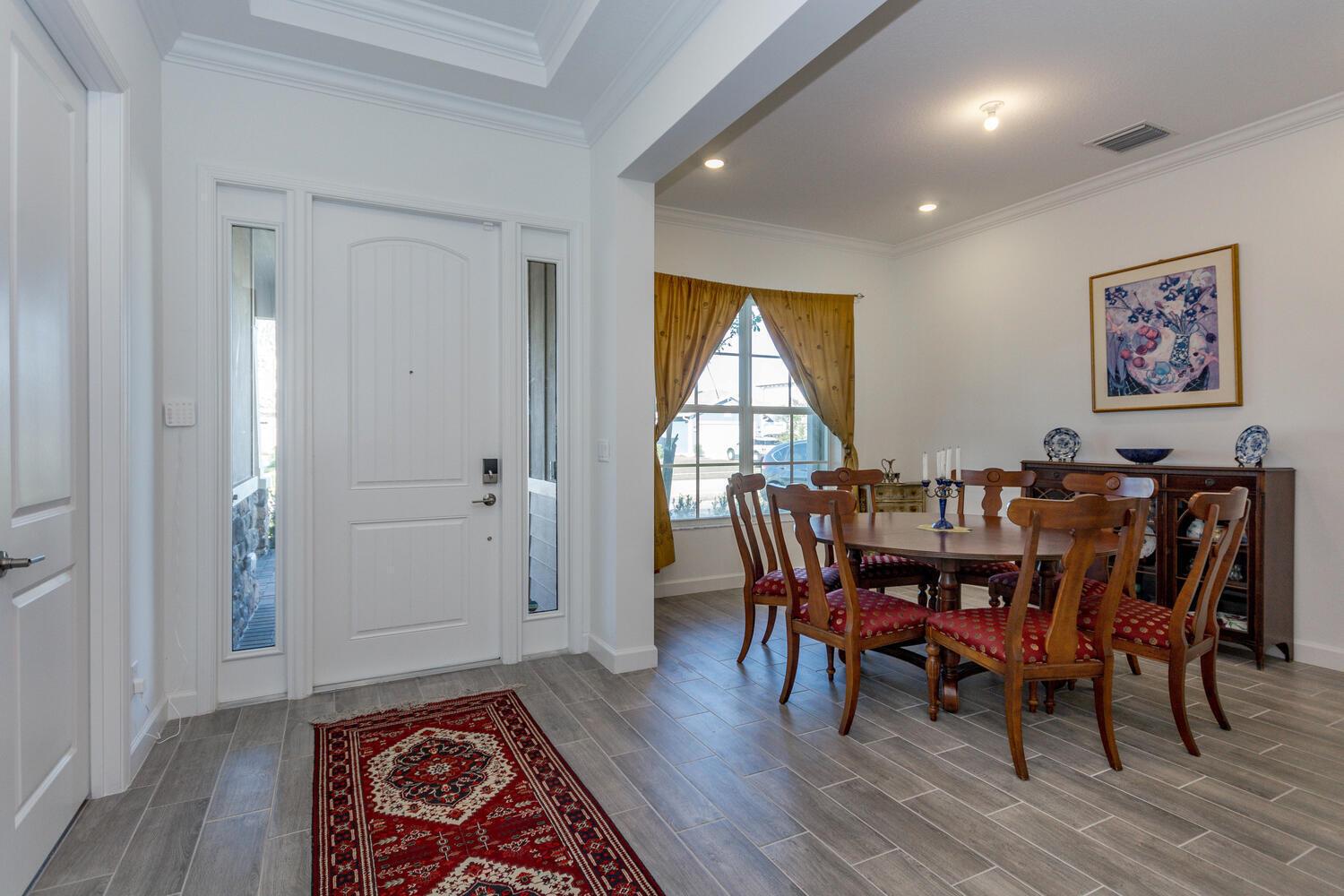 A dining room with a wooden table and chairs sits adjacent to a white entryway — 714 Hookline Circle, Loxahatchee FL 33470, LOXAHATCHEE, FL
