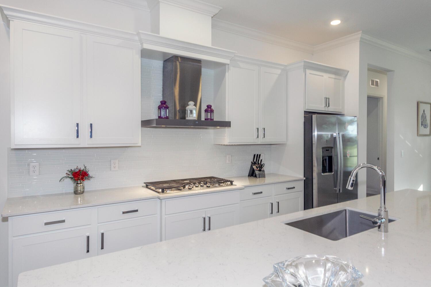 A modern white kitchen features stainless steel appliances, quartz countertops, and a large center island — 714 Hookline Circle, Loxahatchee FL 33470, LOXAHATCHEE, FL