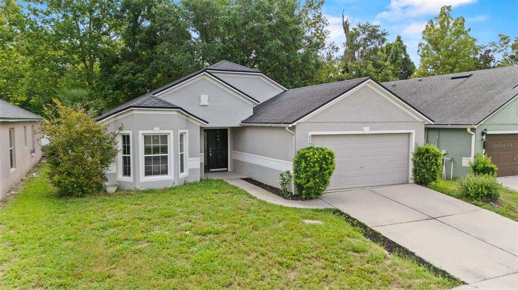 A single-story house with a gray stucco exterior, a two-car garage, and a bay window — 634 SPRING CAVERN AVENUE, ORANGE CITY, FL