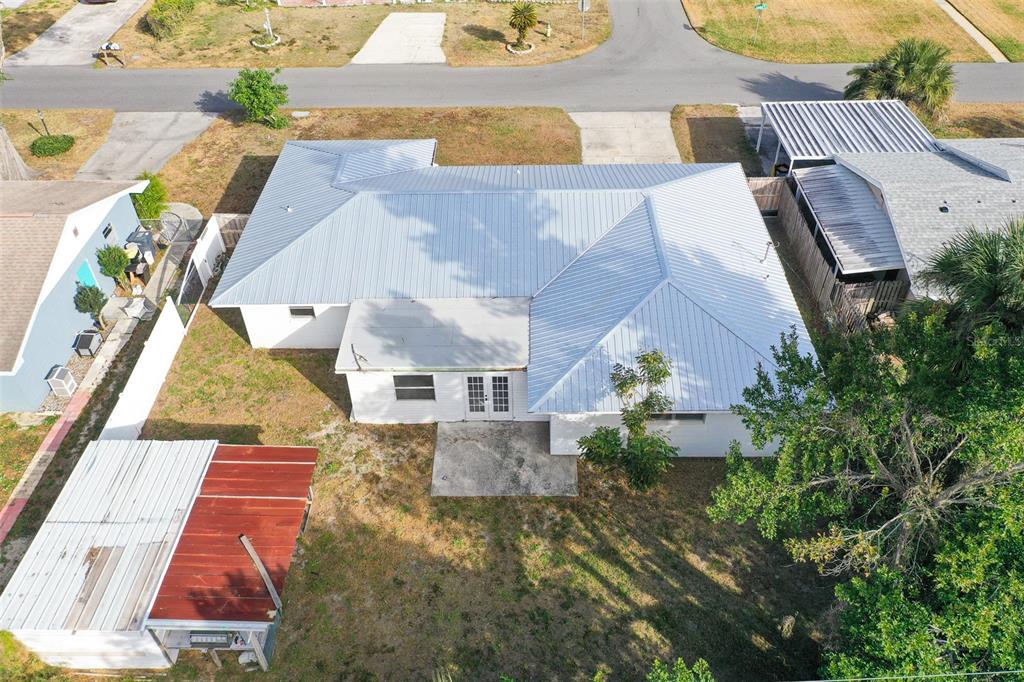 An aerial view shows a house with a metal roof, a patio, and a detached shed — 124 SHELLEY DRIVE, WINTER HAVEN, FL
