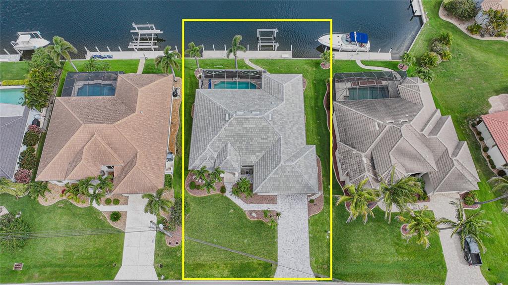 An aerial view shows a waterfront house with a pool, screened lanai, and private dock — 454 MACEDONIA DRIVE, PUNTA GORDA, FL