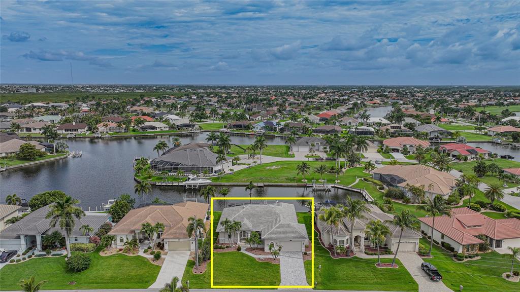 An aerial view shows a single-story house with a tiled roof and a paved driveway — 454 MACEDONIA DRIVE, PUNTA GORDA, FL