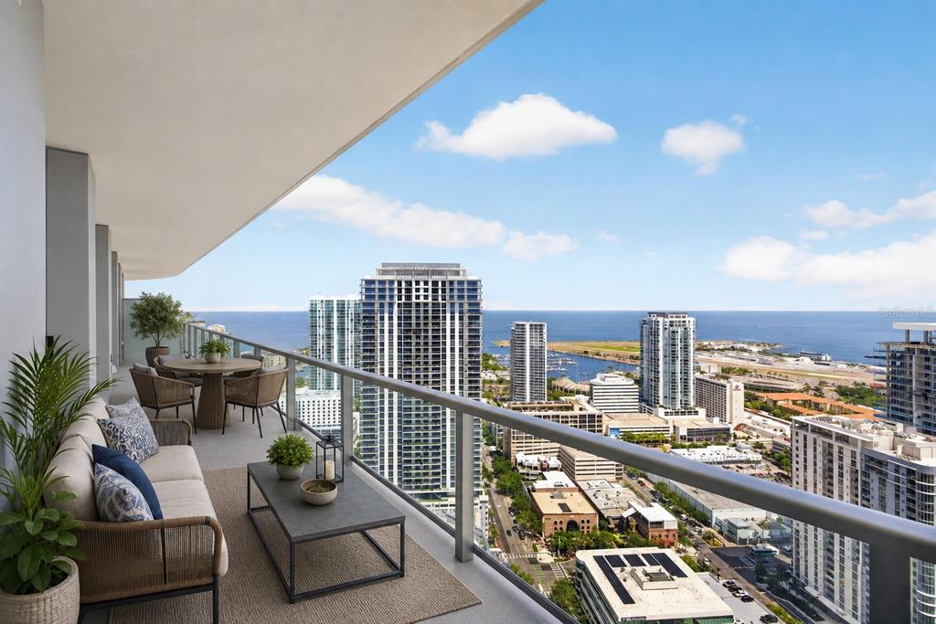 A balcony with outdoor furniture overlooks a city skyline and a large body of water — 400 CENTRAL AVENUE UNIT 3706, ST PETERSBURG, FL