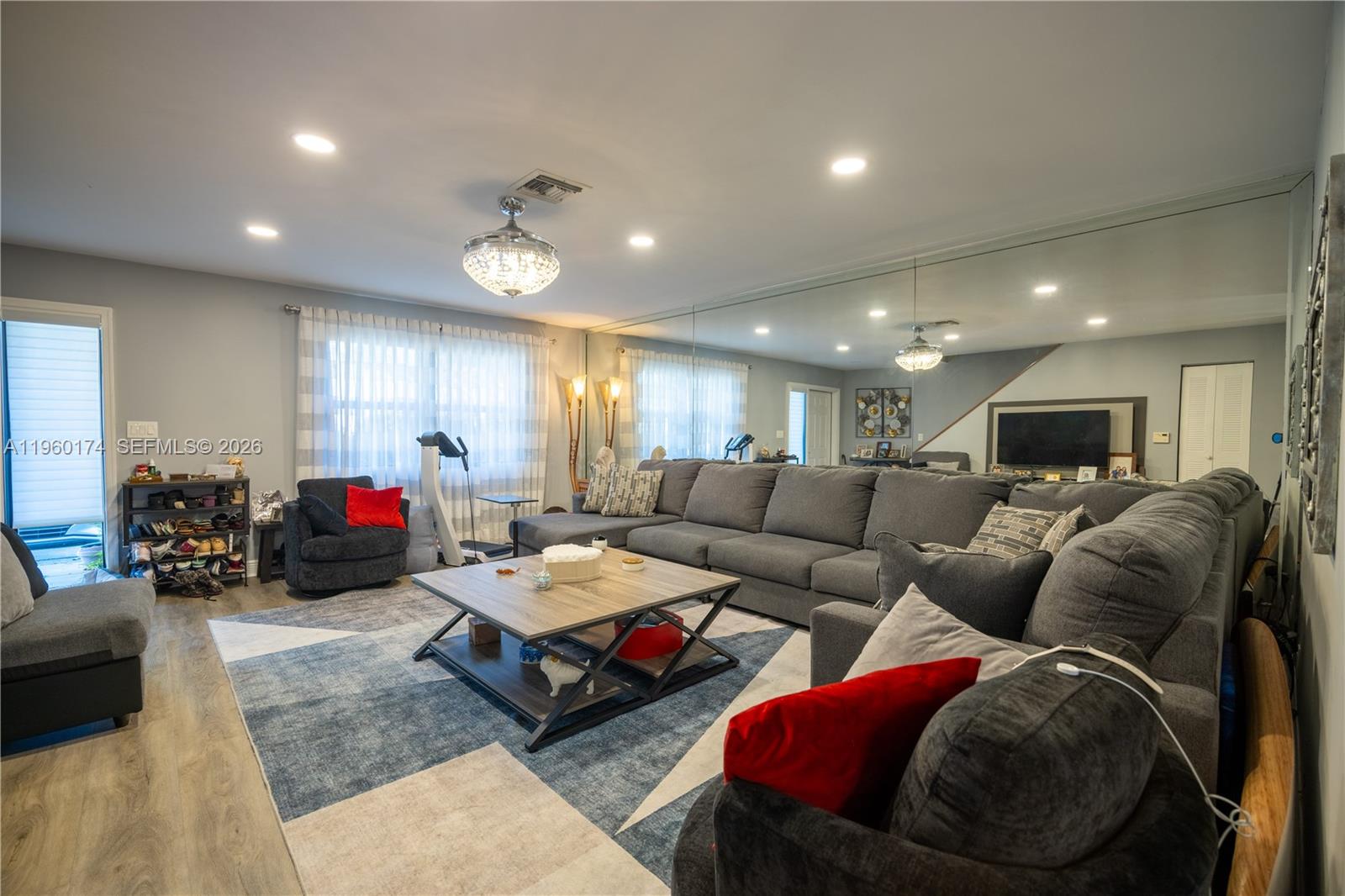 A living room features a large gray sectional sofa, a coffee table, and mirrored walls — 898 NW 47th St, Deerfield Beach FL 33064, DEERFIELD BEACH, FL