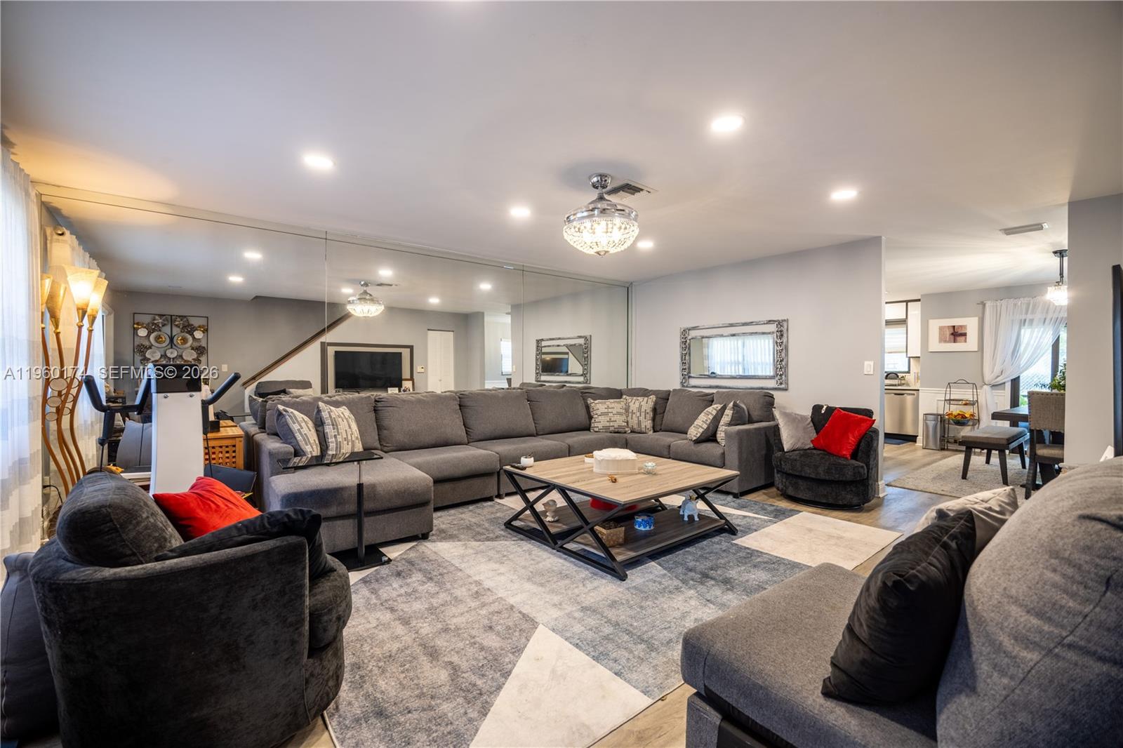 A living room features a large gray sectional, a coffee table, and a mirrored wall — 898 NW 47th St, Deerfield Beach FL 33064, DEERFIELD BEACH, FL