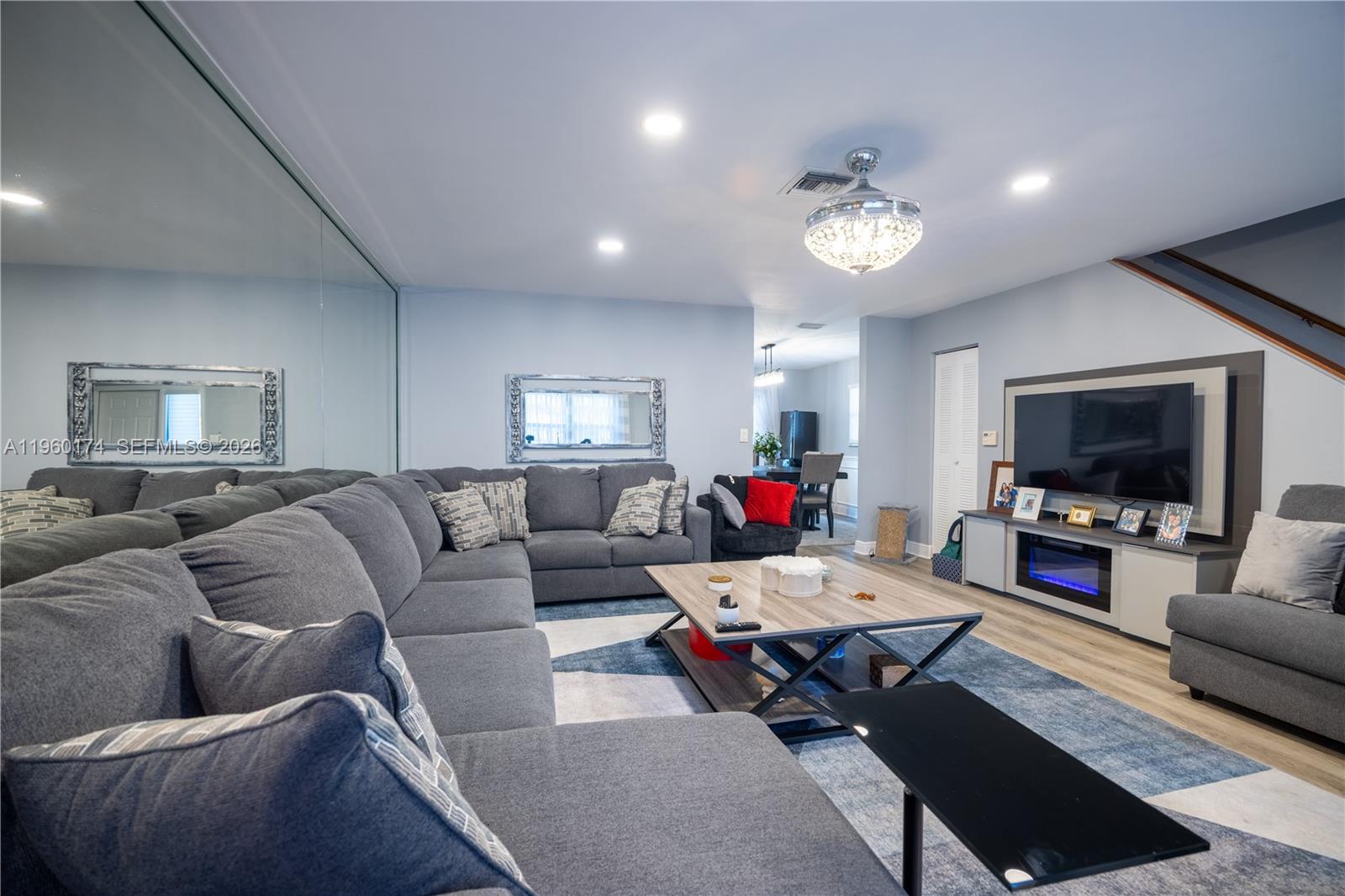 A living room features a large gray sectional sofa, a coffee table, and a wall-mounted television — 898 NW 47th St, Deerfield Beach FL 33064, DEERFIELD BEACH, FL