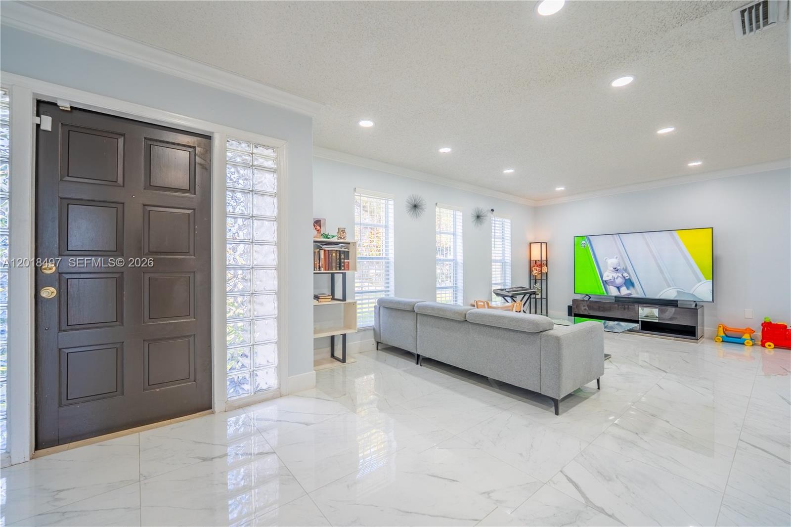 A living room features white marble floors, a gray sectional sofa, and a television — 10750 SW 173rd St, Miami FL 33157, MIAMI, FL