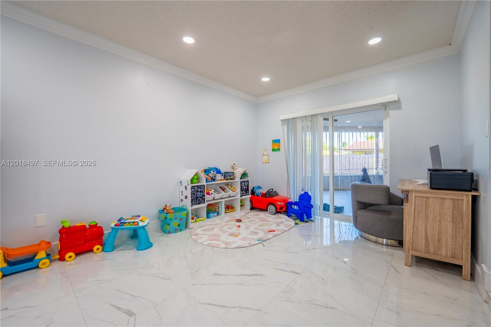 A playroom with white marble-style flooring, a toy storage unit, and a sliding glass door — 10750 SW 173rd St, Miami FL 33157, MIAMI, FL