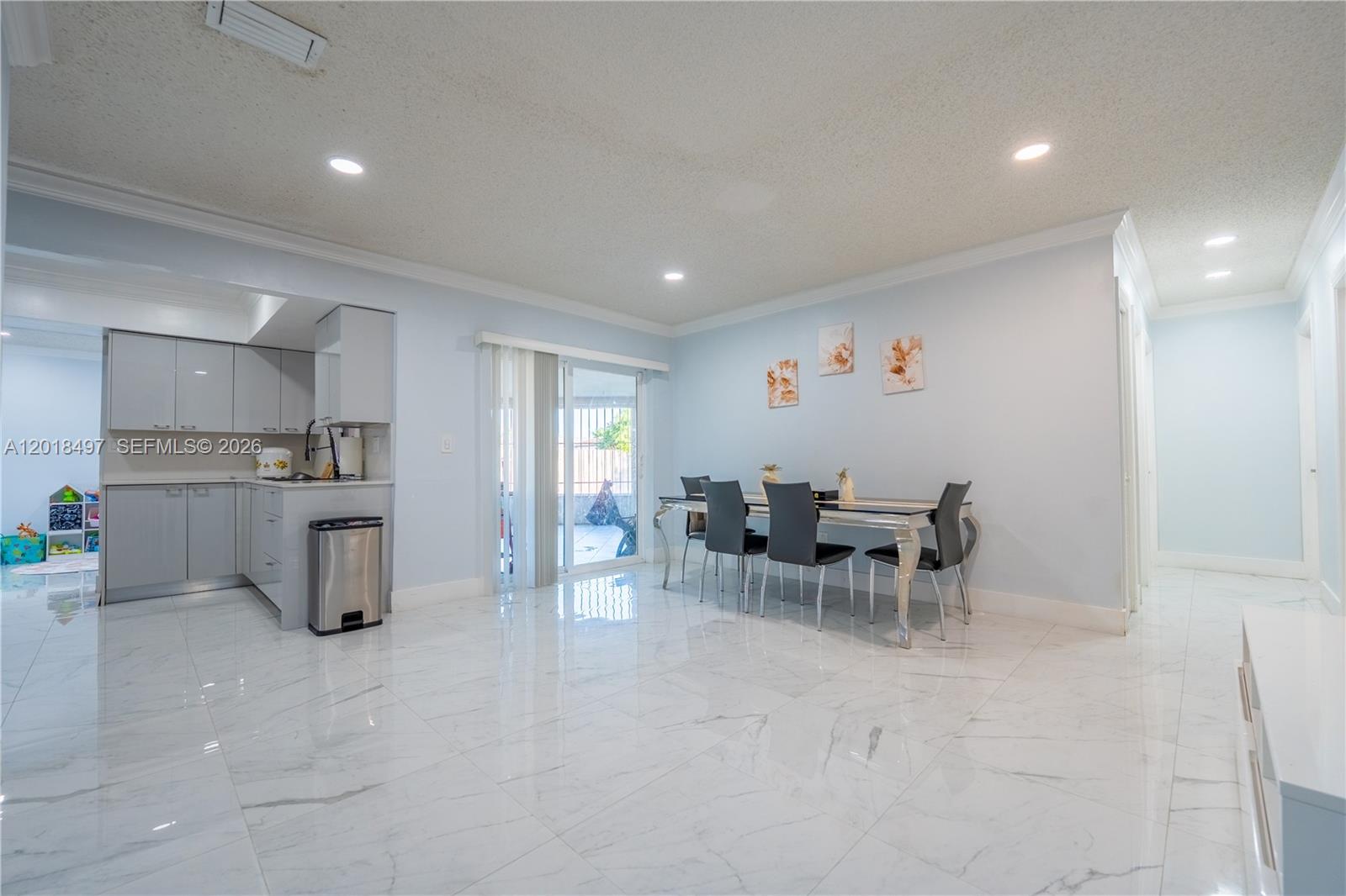 A dining area with a glass table and chairs sits next to a modern kitchen — 10750 SW 173rd St, Miami FL 33157, MIAMI, FL