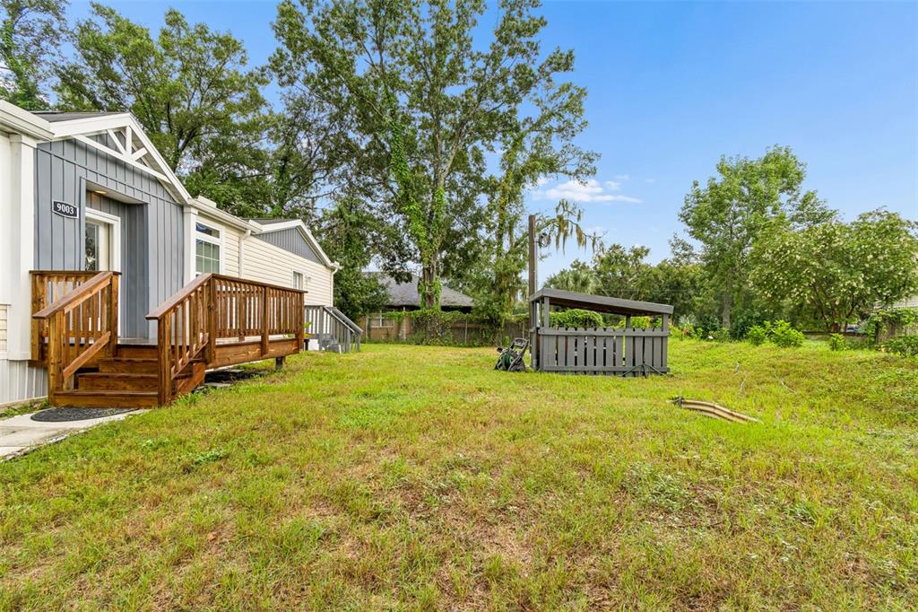A side view of a house with a wooden deck and a small fenced structure — 9003 SCOTT WILSON LANE, ODESSA, FL