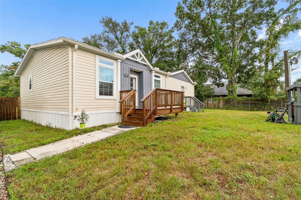 A single-story manufactured home with beige siding, a gray entryway, and a wooden front deck — 9003 SCOTT WILSON LANE, ODESSA, FL