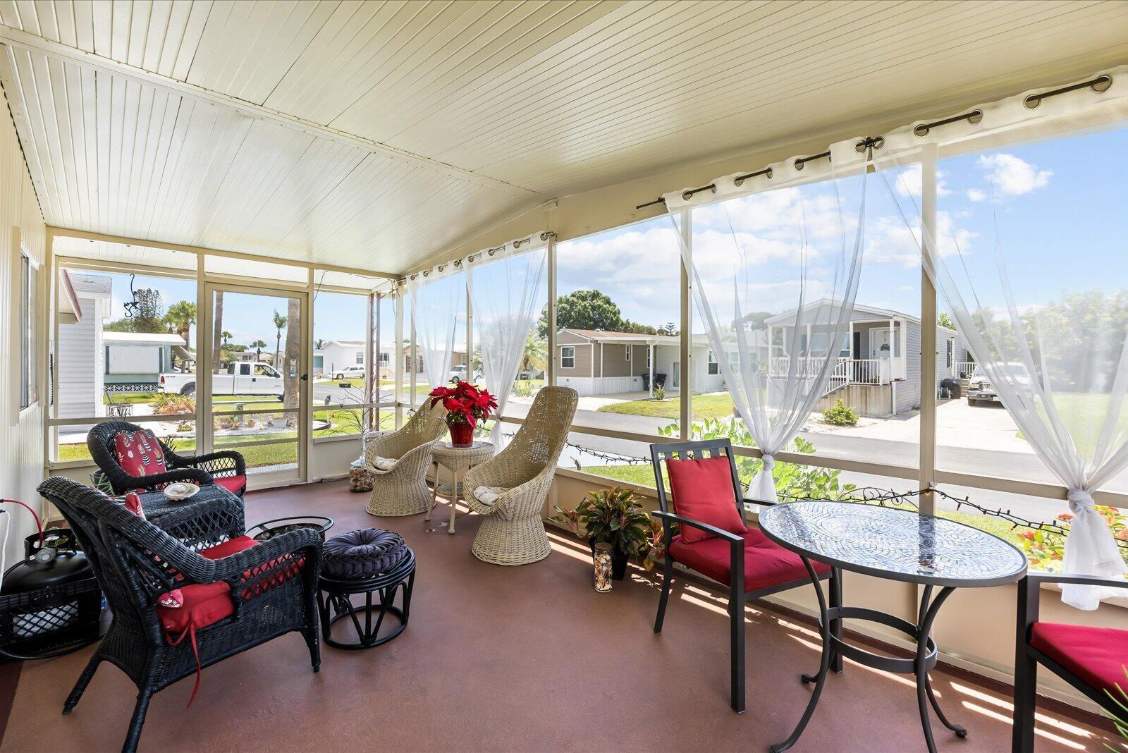 A screened-in porch features wicker furniture, a small dining set, and views of a residential street — 65 Manor Drive, Fort Pierce FL 34982, FORT PIERCE, FL