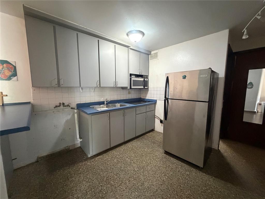 A kitchen features gray cabinets, a blue countertop, a stainless steel refrigerator, and speckled flooring — Apt 207 BORINQUEN TOWERS UNIT 207, SAN JUAN, PR