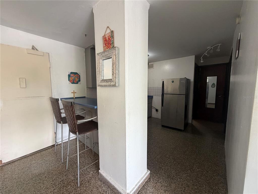 A kitchen area features a breakfast bar with two stools and a stainless steel refrigerator — Apt 207 BORINQUEN TOWERS UNIT 207, SAN JUAN, PR