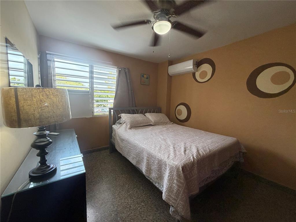 A bedroom features a bed, a dresser with a lamp, and circular wall decorations — Apt 207 BORINQUEN TOWERS UNIT 207, SAN JUAN, PR