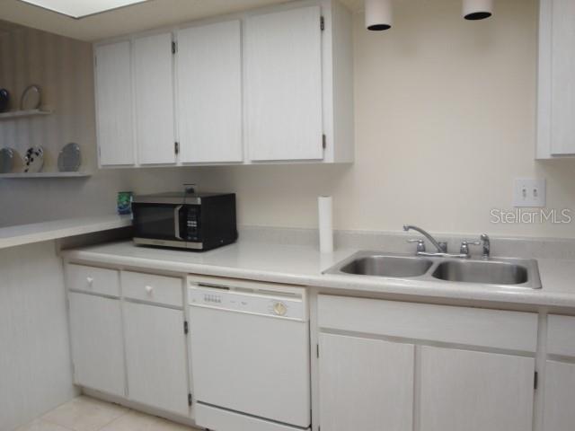 A kitchen features white cabinets, a double sink, a dishwasher, and a black microwave — 500 TREASURE ISLAND CAUSEWAY UNIT 202, TREASURE ISLAND, FL