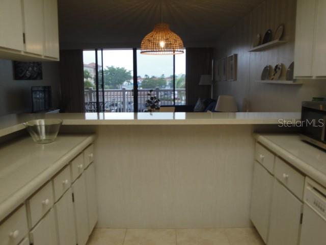 A kitchen with white cabinets and a breakfast bar overlooking a living area and balcony — 500 TREASURE ISLAND CAUSEWAY UNIT 202, TREASURE ISLAND, FL