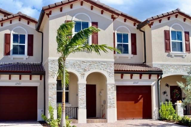 The exterior of a two-story townhouse features a stone-veneer entryway, a dark door, and a garage — 12517 NW 23rd Pl, Miami FL 33167, MIAMI, FL
