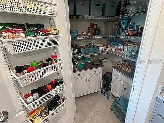 A walk-in pantry features white cabinetry, wire shelving, and an over-the-door spice rack — 2711 NEVERLAND DRIVE, NEW SMYRNA BEACH, FL